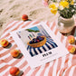 Plum – White village Urban Café Scene, Fruit Wall Illustration, unframed on coastal sand